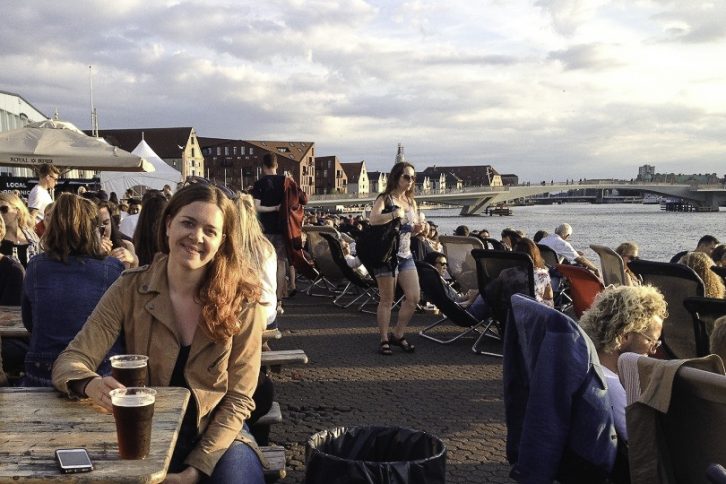 Guro Thobru underveis på reise med buss og tog til Brussel. Her med en øl i dansk solnedgang.