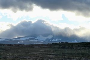 Snøhetta, 2286 moh, leker gjemsel på dette bildet, men bak skyene er dette Norges høyeste fjell utenfor Jotunheimen. (Foto tatt på tilbaketuren, i litt annet vær enn de andre bildene.)
