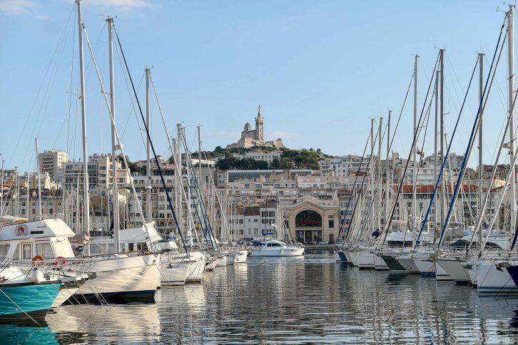 Den gamle havnen, Vieux Port, med utsikt opp på basilikaen Notre Dame de la Garde. På en ferie til Syden med tog kan vi velge å bli i Marseille, eller bruke byen som utgangspunkt for reiser til andre kystbyer langs Middelhavet.
